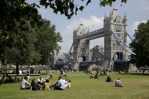 People relax in the sun during lunchtime as they sit in Potters Fields Park, backdropped by the Tower Bridge, in London, Thursday, June 28, 2018. (AP Photo/Matt Dunham)