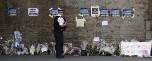 A police officer stands near floral tributes in Finsbury Park after an incident where a van struck pedestrians, in London, Monday June 19, 2017. British authorities and Islamic leaders moved swiftly to ease concerns in the Muslim community after a man plowed his vehicle into a crowd of worshippers outside a north London mosque early Monday, injuring at least nine people. (AP Photo/Frank Augstein)