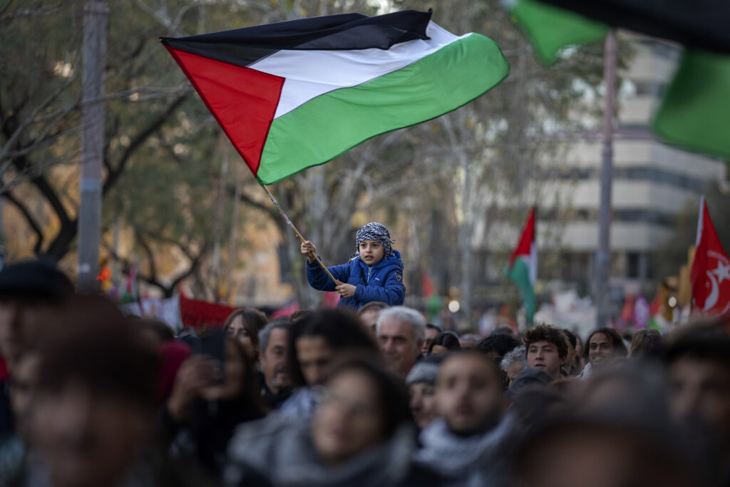 A boy waves a Palestinian flag as demonstrators march during a protest in support of Palestinians and calling for an immediate ceasefire in Gaza, in Barcelona, Spain, Saturday, Jan. 20, 2024