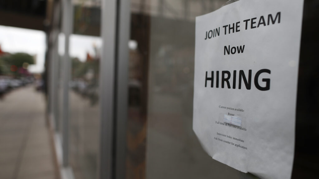 photo of a now hiring sign on the window of a restaurant