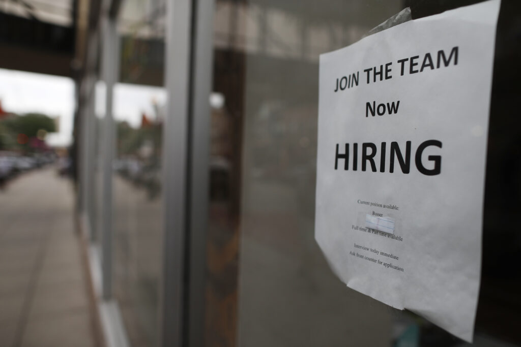 photo of a now hiring sign on the window of a restaurant